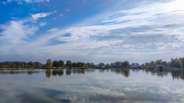Mükemmel gölde güneşli bir gün. Suda yansıması olan sonbahar gölü. Güneşli bir günde bulutlu bir gökyüzü.