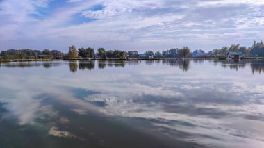 Mükemmel gölde güneşli bir gün. Suda yansıması olan sonbahar gölü. Güneşli bir günde bulutlu bir gökyüzü.