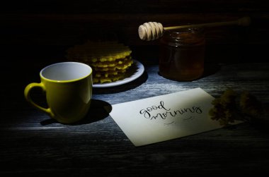 Ahşap arka planda bir fincan kahve ve waffle ile sakin bir hayat. Fotoğraf hafif anahtarla çekilmiş..