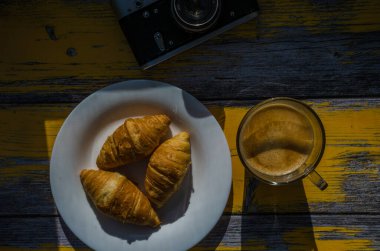 Arka planda retro kamera ve bir fincan kahveyle sakin bir hayat. Tahta arka plandaki tabakta tatlılar