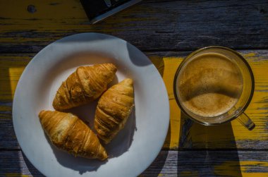 Arka planda retro kamera ve bir fincan kahveyle sakin bir hayat. Tahta arka plandaki tabakta tatlılar