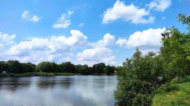 Bir göl manzarası ve yaz mevsiminde gökyüzünde bulutlar