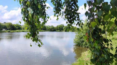 Bir göl manzarası ve yaz mevsiminde gökyüzünde bulutlar