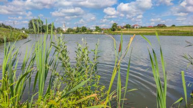 Bir göl manzarası ve yaz mevsiminde gökyüzünde bulutlar