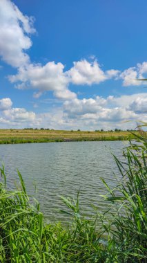 Bir göl manzarası ve yaz mevsiminde gökyüzünde bulutlar