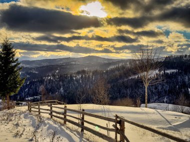 Karlı, gizemli Karpatlar bulutlu gökyüzünün altında güneşli bir havada