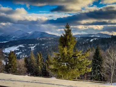 Karlı, gizemli Karpatlar bulutlu gökyüzünün altında güneşli bir havada