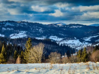 Karlı, gizemli Karpatlar bulutlu gökyüzünün altında güneşli bir havada