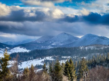 Karlı, gizemli Karpatlar bulutlu gökyüzünün altında güneşli bir havada