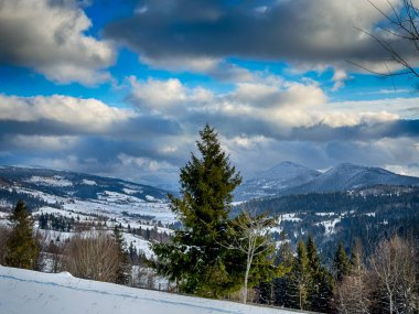Karlı, gizemli Karpatlar bulutlu gökyüzünün altında güneşli bir havada