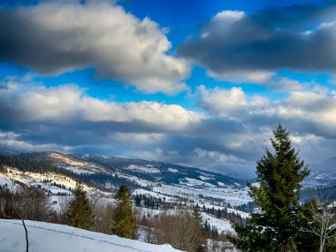 Karlı, gizemli Karpatlar bulutlu gökyüzünün altında güneşli bir havada
