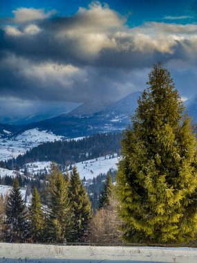 Karlı, gizemli Karpatlar bulutlu gökyüzünün altında güneşli bir havada