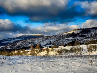 Karlı, gizemli Karpatlar bulutlu gökyüzünün altında güneşli bir havada