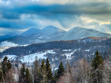 Karlı, gizemli Karpatlar bulutlu gökyüzünün altında güneşli bir havada
