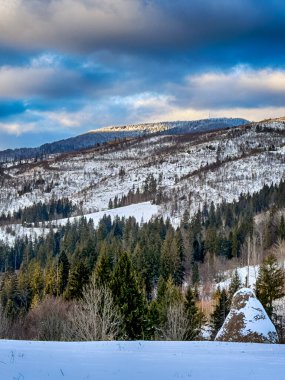 Karlı, gizemli Karpatlar bulutlu gökyüzünün altında güneşli bir havada
