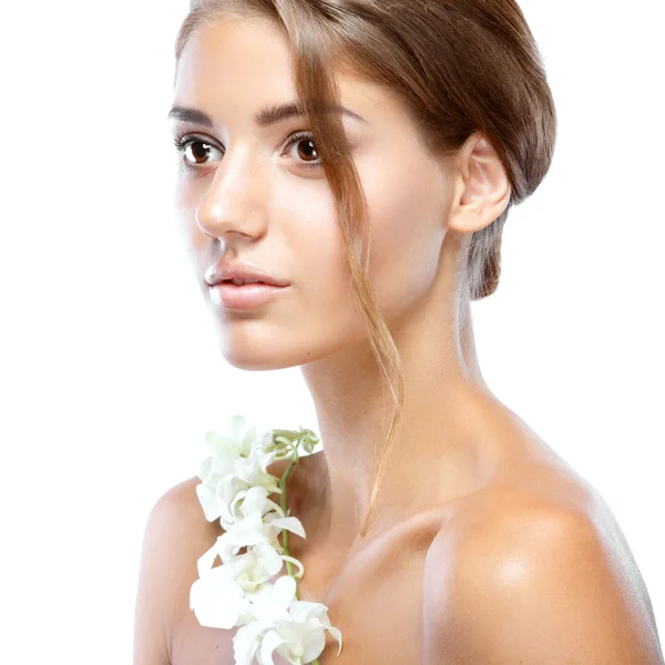 Jovem mulher com rosto claro natural compõem seu cabelo com uma flor branca em um fundo claro — Fotografia de Stock