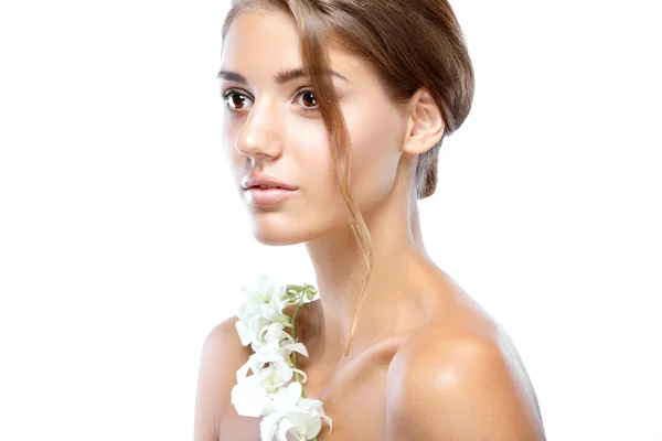 Young woman with clear face natural make up her hair up with a white flower on a light background — Stock Photo, Image