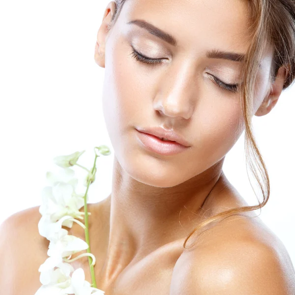 Молодая женщина с ясным лицом натуральный макияж ее волосы с белым цветком на светлом фоне — стоковое фото