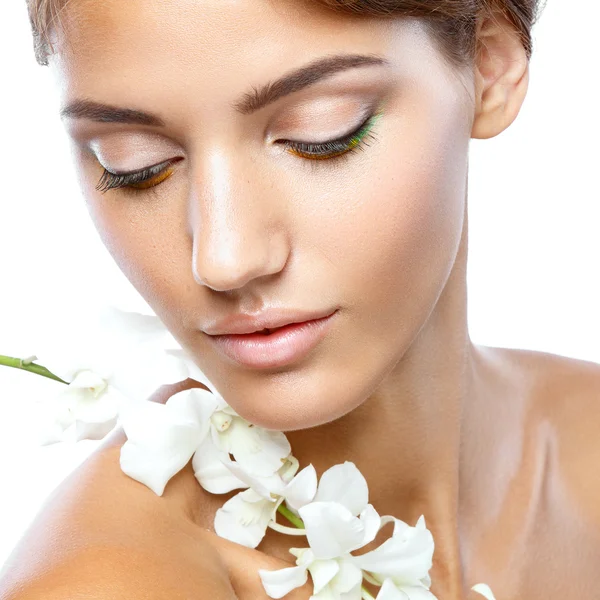 Young woman with clear face natural make up her hair up with a white flower on a light background — Stock Photo, Image