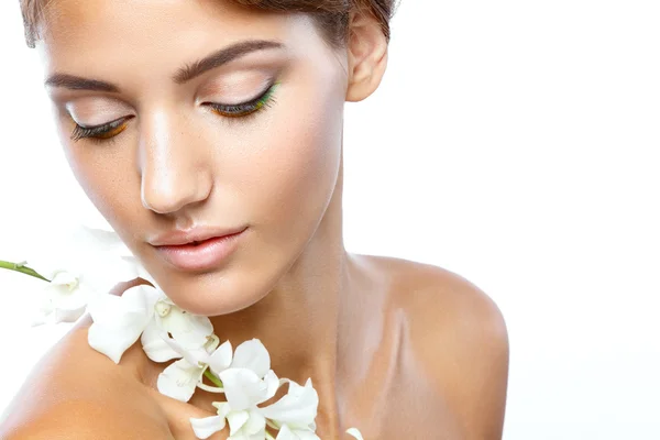 Jonge vrouw met duidelijk gezicht natuurlijke haar make-up omhoog met een witte bloem op een lichte achtergrond — Stockfoto