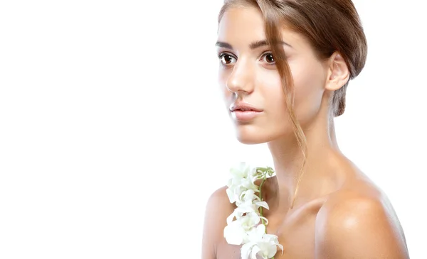 Young woman with clear face natural make up her hair up with a white flower on a light background — Stock Photo, Image