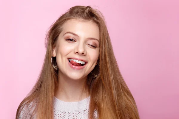 Mujer joven guapa guiñando un ojo, sonriendo en el fondo rosa . —  Fotos de Stock