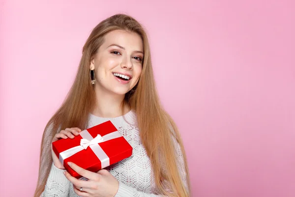 Radosna dziewczyna w biały sweterek z czerwonym prezent pudełko na różowym tle, Walentynki, święta, szczęście, Międzynarodowy Dzień kobiet Obrazek Stockowy