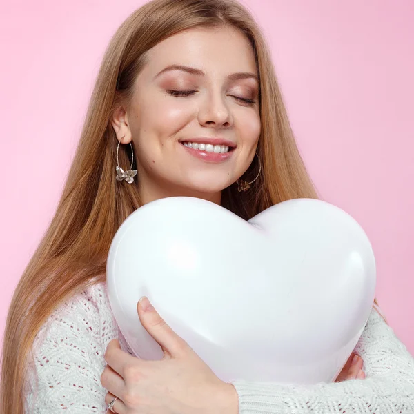 Söt blond kvinna med en hjärtformad ballong. Studio porträtt över rosa bakgrund. Grattis på födelsedagen. Alla hjärtans dag. Joyful — Stockfoto