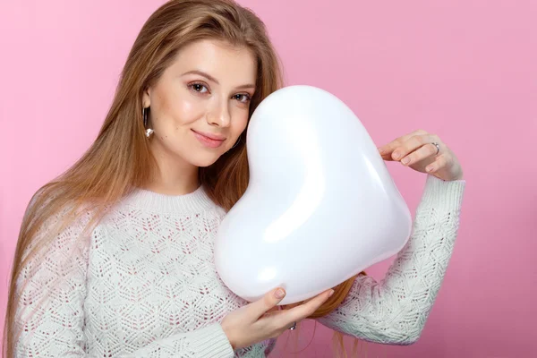 Söt blond kvinna med en hjärtformad ballong. Studio porträtt över rosa bakgrund. Grattis på födelsedagen. Alla hjärtans dag. Joyful — Stockfoto