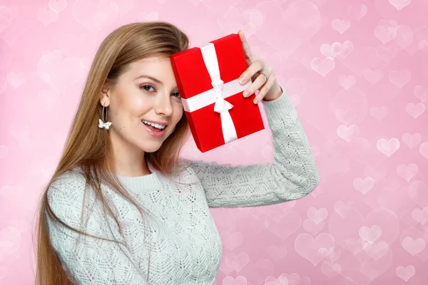 San Valentino. Dolce donna bionda con in mano una scatola regalo. cuore bokeh sfondo Gioioso — Foto Stock