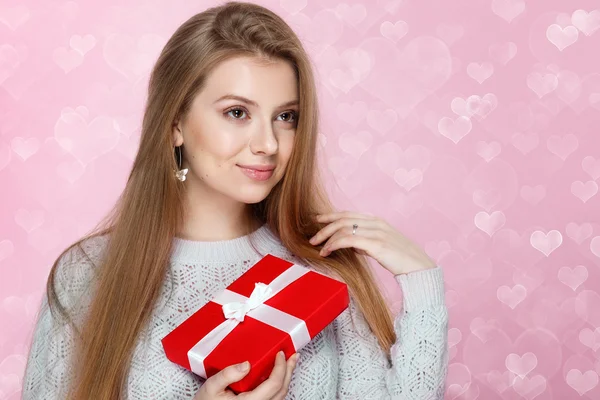 Valentines Day. Sweet blonde woman holding a gift box. heartshaped bokeh background Joyful — Stock Photo, Image