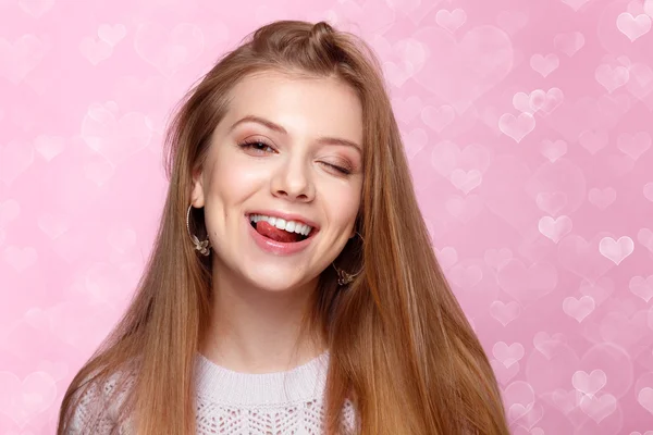 Dulce mujer rubia sonriendo, guiñando un ojo. Día de San Valentín. fondo bokeh en forma de corazón alegre —  Fotos de Stock