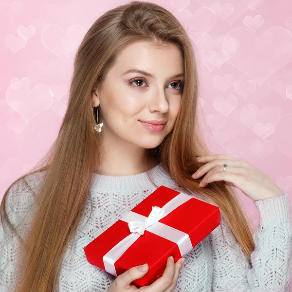 Día de San Valentín. Mujer rubia dulce sosteniendo una caja de regalo. fondo bokeh en forma de corazón alegre —  Fotos de Stock