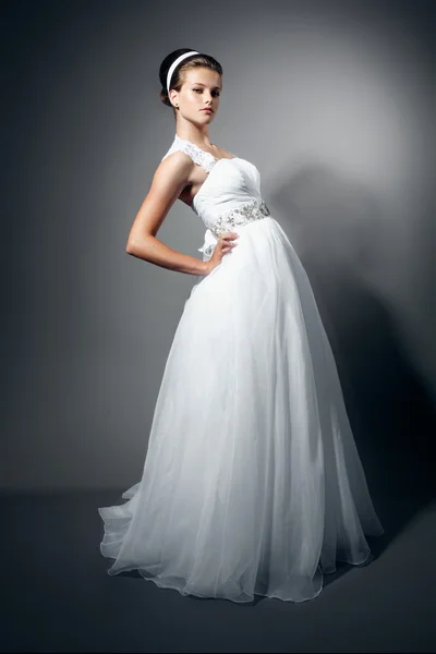 Bela noiva jovem em um vestido branco de casamento no fundo elegante cinza — Fotografia de Stock