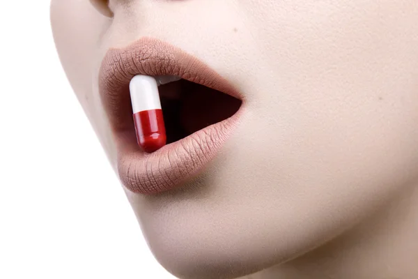 Zbliżenie twarzy z czerwoną pigułkę biały medycyny w jej ustach Obraz Stockowy