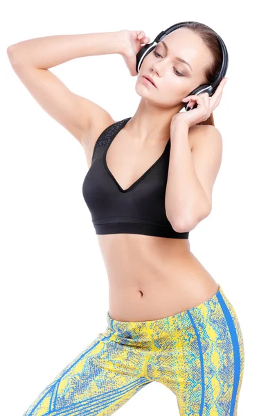 Entrenamiento de modelo femenino deportivo con auriculares en ropa deportiva de moda. Estudio de rodaje . — Foto de Stock