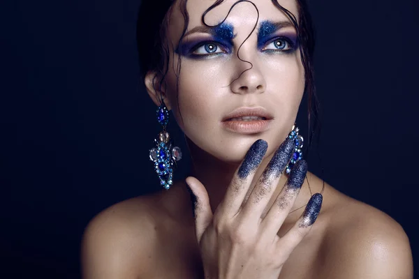 Tournage de beauté, mannequin avec le maquillage brillant bleu nuit, coiffure mouillée et tinsel sur ses doigts — Photo