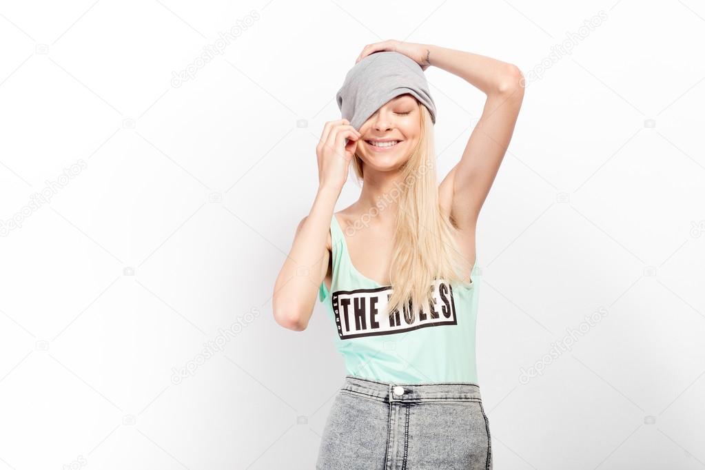 Young blonde model posing ans smiles on a white background. Fasion shootina at the studio.