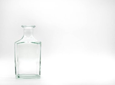 Beyaz arka planda tek bir boş cam şişe. Şeffaf kare şişe. Dikey, renksiz kavanozun ön görünümü.
