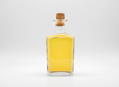 Beyaz arka planda izole edilmiş mantar kapaklı, alkollü cam şişe. Sarı sıvı ile şeffaf kare şişe. Dikey konaklama kavanozunun ön görünümü.