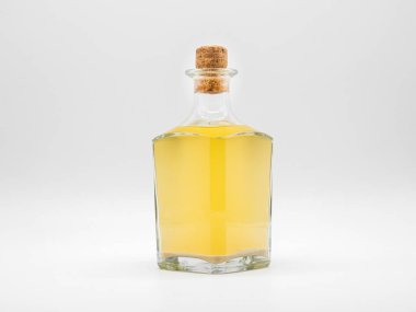 Beyaz arka planda izole edilmiş mantar kapaklı, alkollü cam şişe. Sarı sıvı ile şeffaf kare şişe. Dikey konaklama kavanozunun ön görünümü.