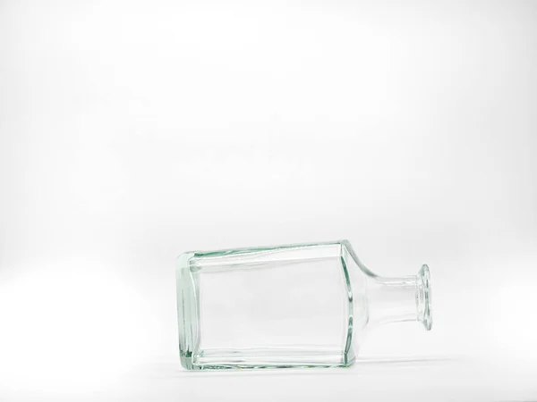 白色背景上的一个空玻璃瓶 透明的正方形瓶子放置在其侧面的透明正方形瓶子的前视图 — 图库照片