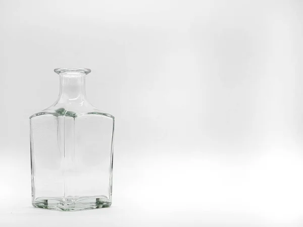 白色背景上的一个空玻璃瓶 透明的正方形瓶子垂直的无色罐子的前视图 — 图库照片