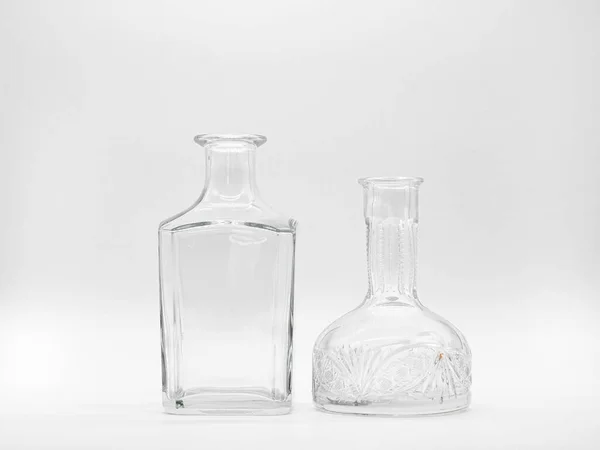 空のガラスカフェと白い背景に隔離された空のガラスボトル 透明なボトルのペア 形が異なる2本の直立した壺の正面図 — ストック写真