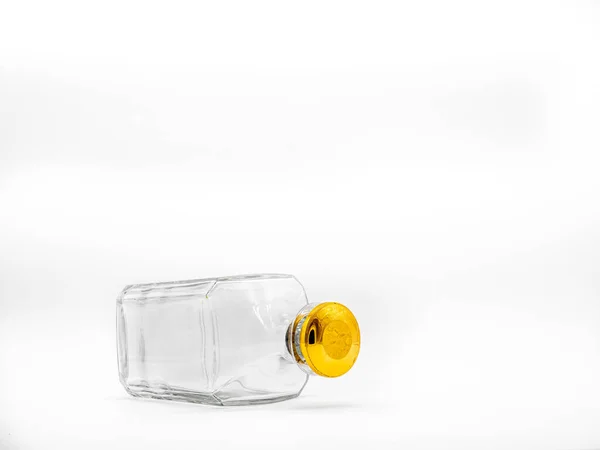 白い背景に大きな金の丸コルクで閉じ空のガラスボトル 横の透明な四角形の瓶の上の敷設の図 — ストック写真