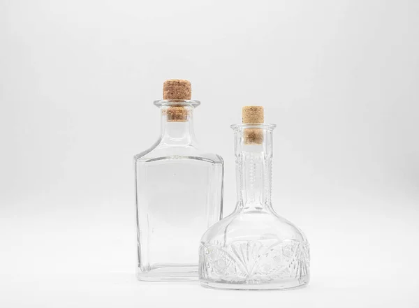 空のガラスカフェと白い背景に隔離されたコルクキャップで閉じられた空のガラスボトル 透明なボトルのペア 形状の異なる二つの垂直滞在瓶の正面図 — ストック写真