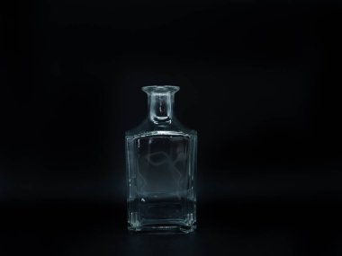 Siyah arka planda tek bir boş cam şişe. Şeffaf kare şişe. Dikey, renksiz kavanozun ön görünümü.