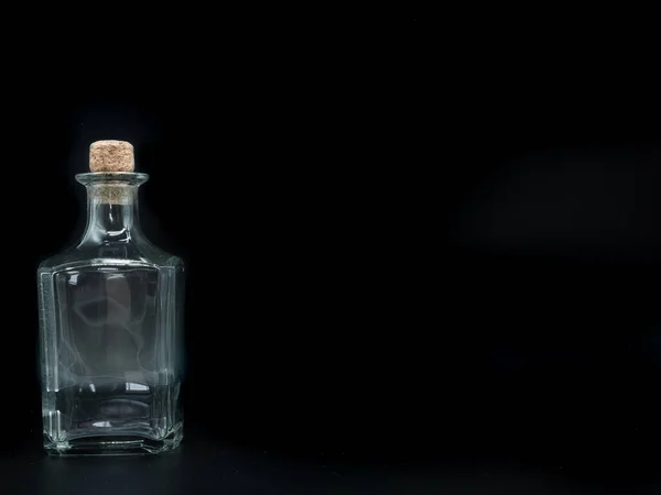 黒の背景に一本の空のガラス瓶 透明な四角いボトル 横の透明な四角形の瓶の上の敷設の正面図 — ストック写真