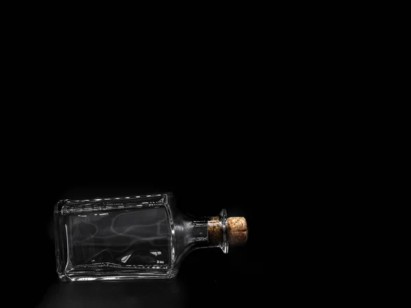 暗い背景に隔離されたコルクキャップで閉じ空のガラスボトル 横の透明な四角形の瓶の上の敷設の正面図 — ストック写真