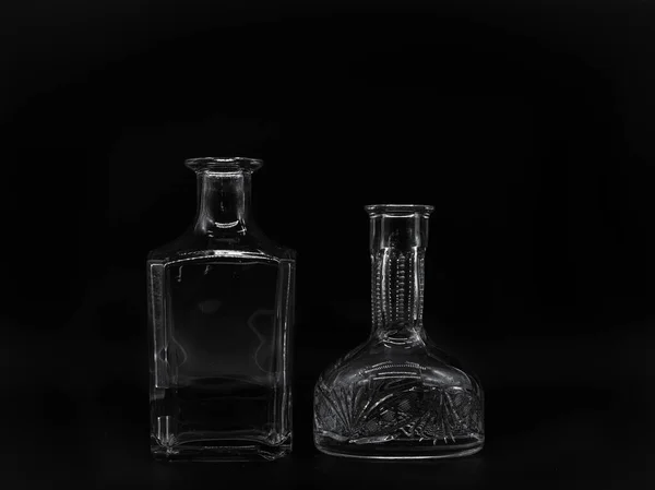 空のガラスカフェと黒の背景に隔離された空のガラスボトル 透明なボトルのペア 形が異なる2本の直立した壺の正面図 — ストック写真